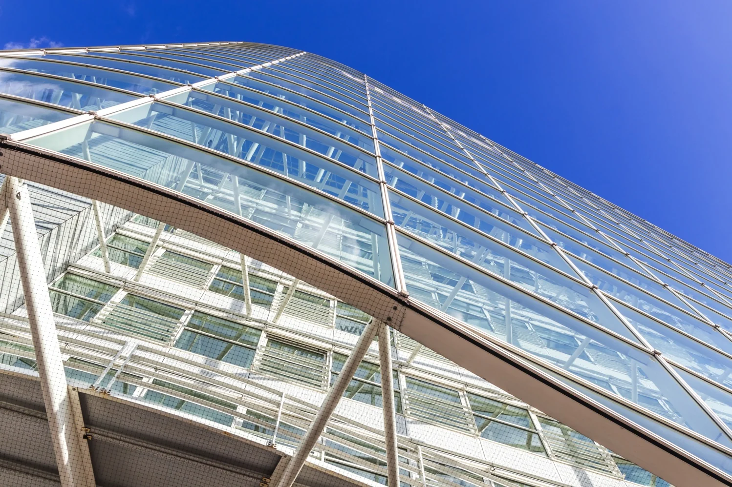 Glazen gevel van een modern kantoorgebouw aan de Reactorweg, gefotografeerd vanaf een laag standpunt tegen een helderblauwe lucht.