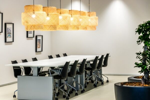 Moderne vergaderruimte aan de Reactorweg met lange witte tafel, zwarte bureaustoelen, hanglampen van rotan en wanddecoratie.