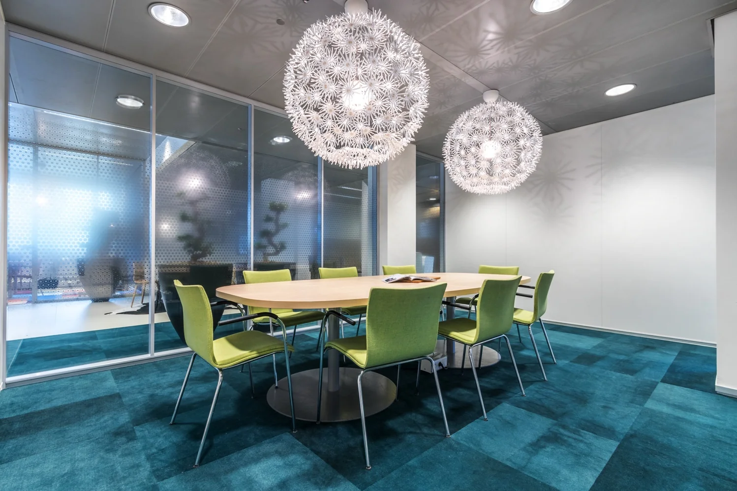 Modern ingerichte vergaderruimte aan de Reactorweg met ovale tafel, groene stoelen en opvallende bolvormige hanglampen.