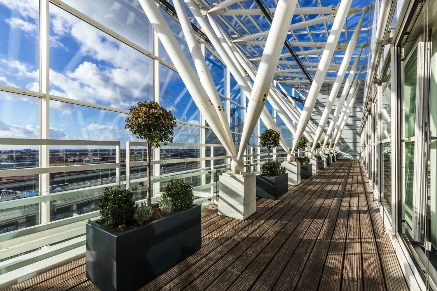 Lichte glazen overdekte loopbrug met plantenbakken op Reactorweg in Utrecht.