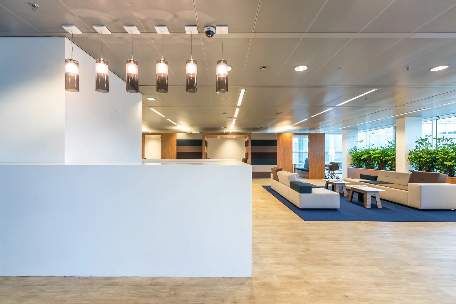 Moderne kantoorruimte aan de Reactorweg met een open zithoek, houten vloer en grote ramen met veel daglicht.