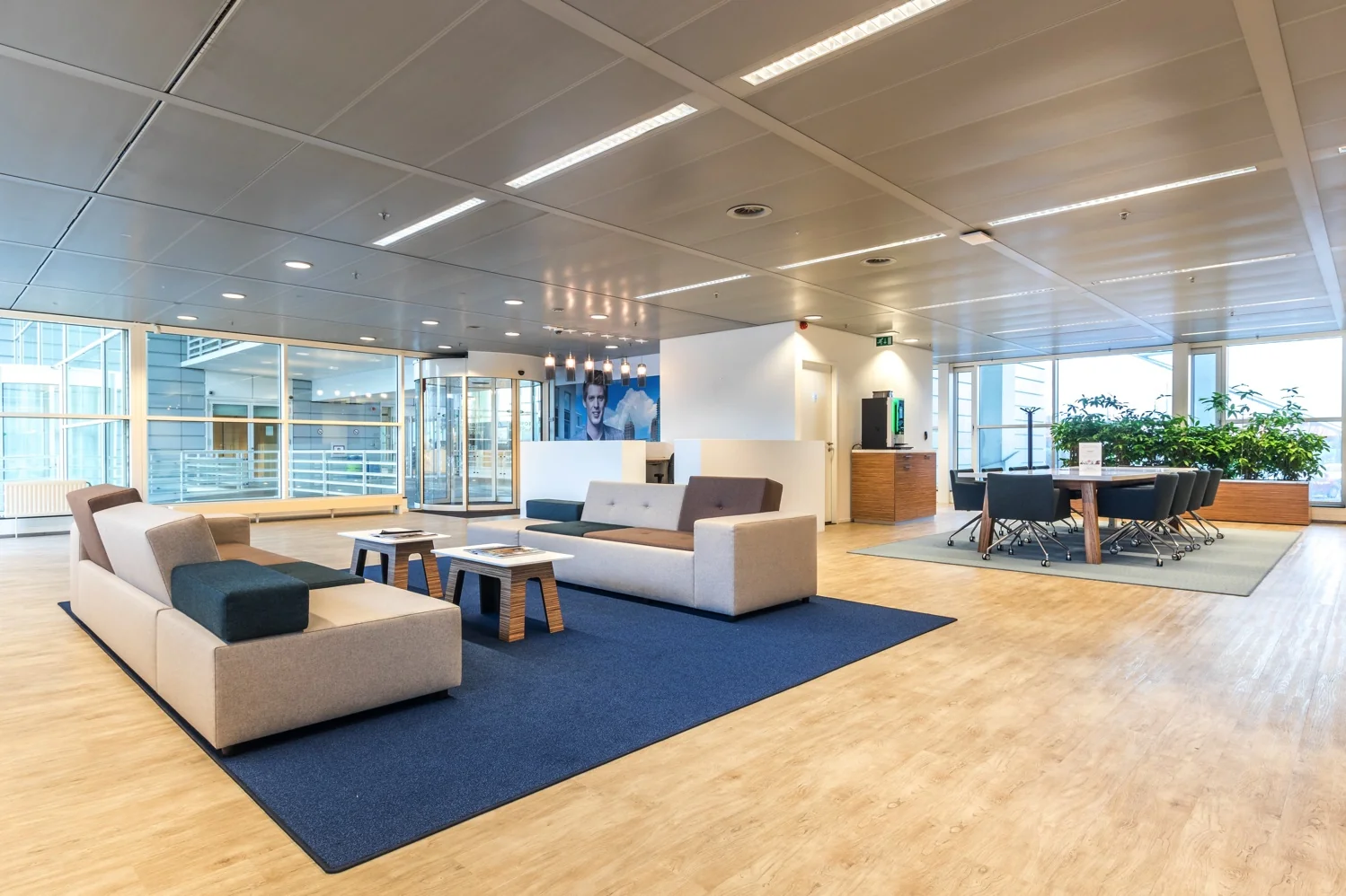 Moderne, open kantoorlounge aan de Reactorweg met zithoeken, vergadertafel en grote ramen.