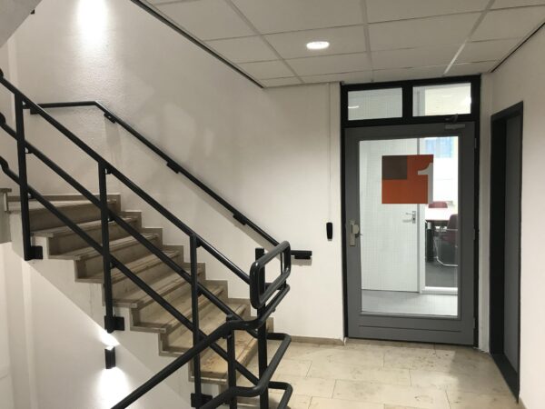 Trapportaal met stalen leuning en glazen deur naar een vergaderruimte in een kantoorpand aan de Cypresbaan.