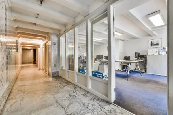 Hal met marmeren vloer en betegelde muren, met zicht op een kantoorruimte aan de Herengracht.