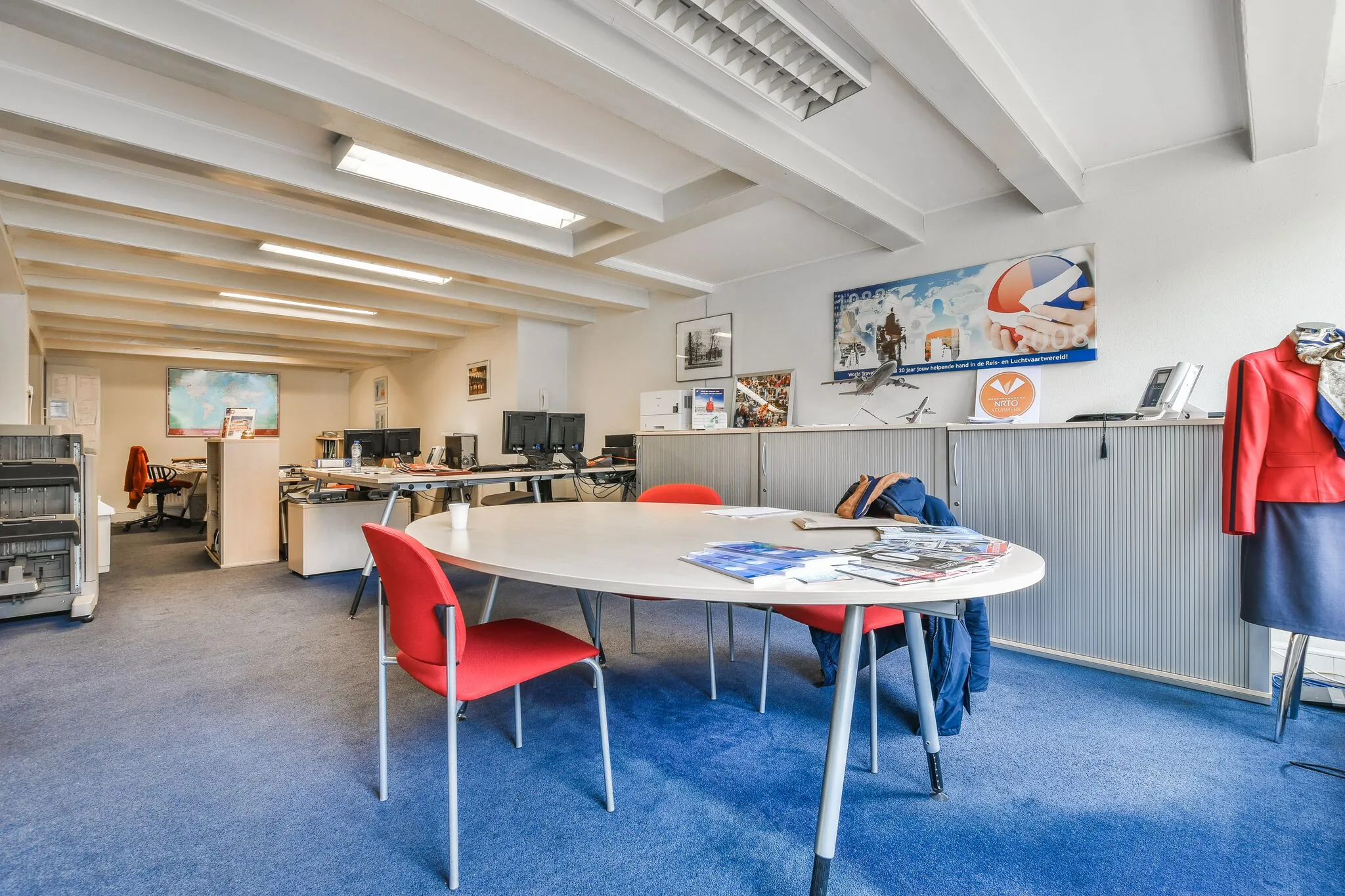 Licht en netjes ingericht kantoor aan de Herengracht met bureaus, computers, een vergadertafel en luchtvaartgerelateerde decoratie.