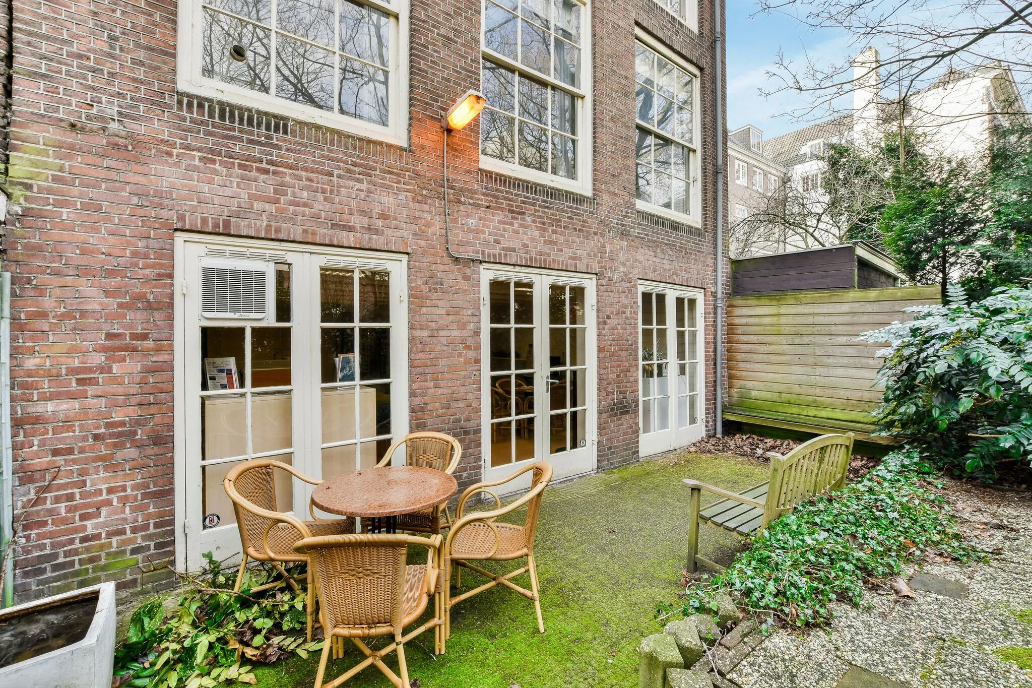Kleine binnentuin aan de Herengracht met terrasmeubilair en toegang tot het pand via meerdere Franse deuren.
