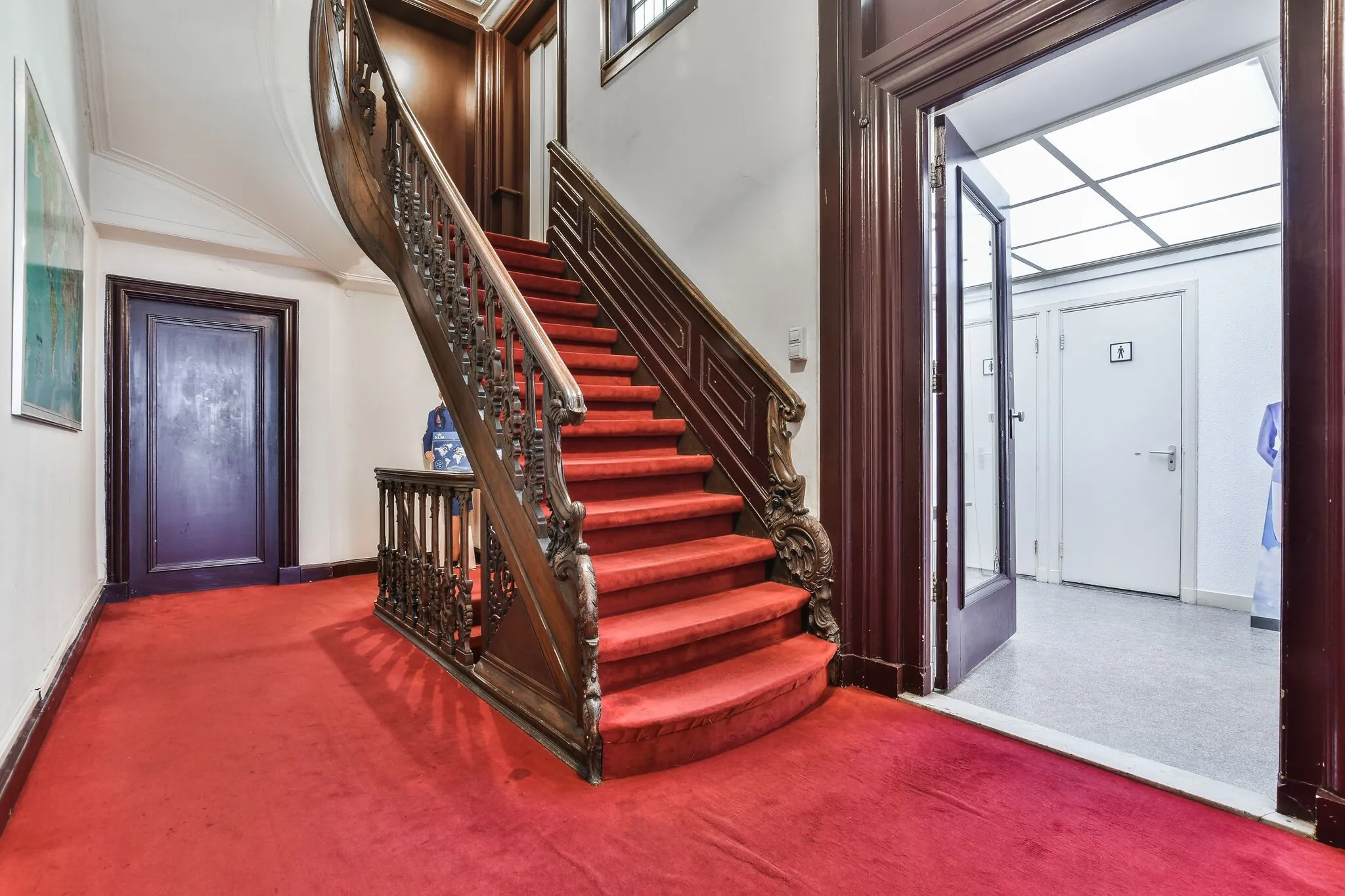 Trap met rode loper en sierlijke houten leuning in een klassiek pand aan de Herengracht.