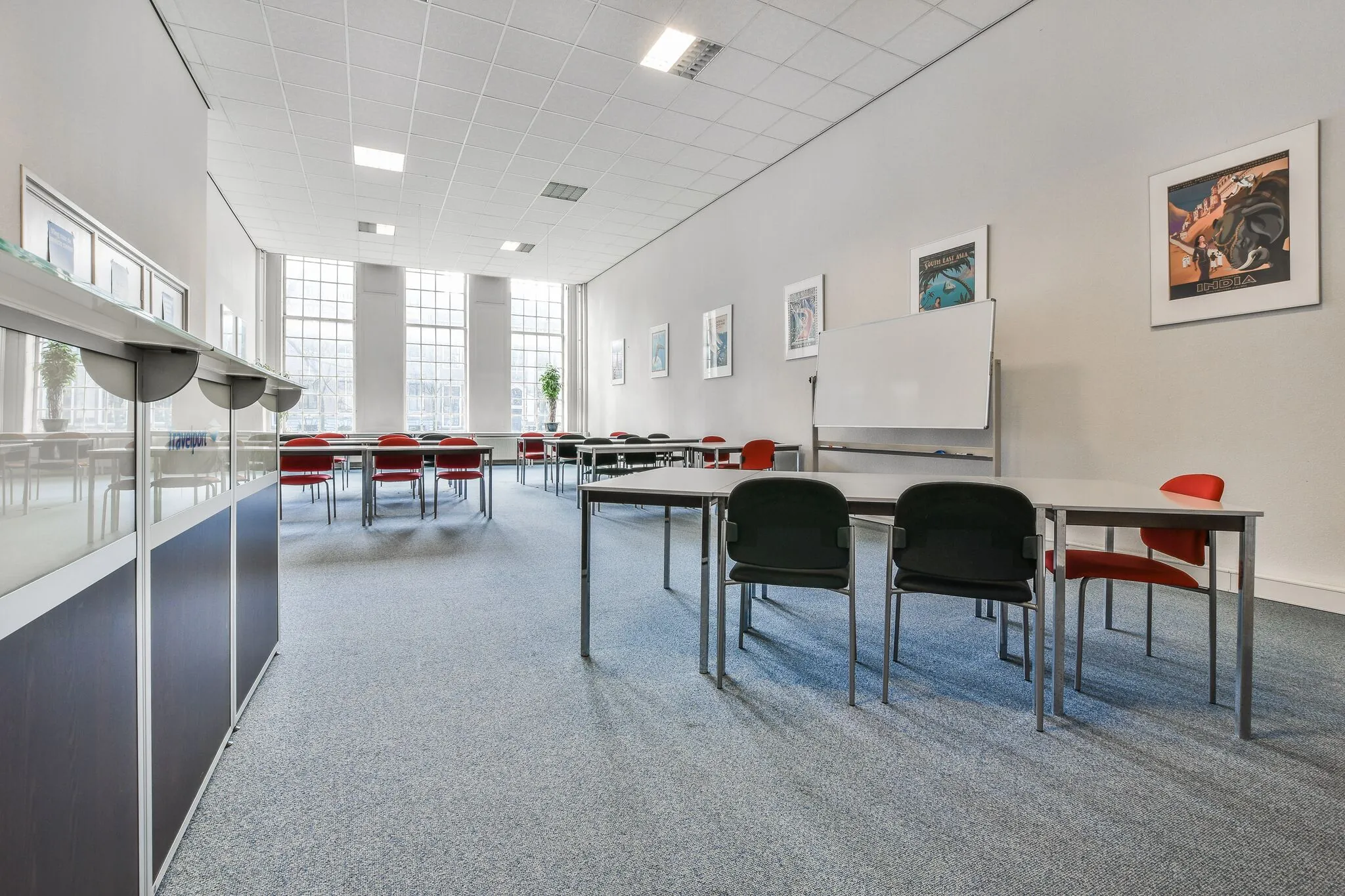 Vergaderruimte aan de Herengracht met grote ramen, moderne tafels, stoelen en een whiteboard.