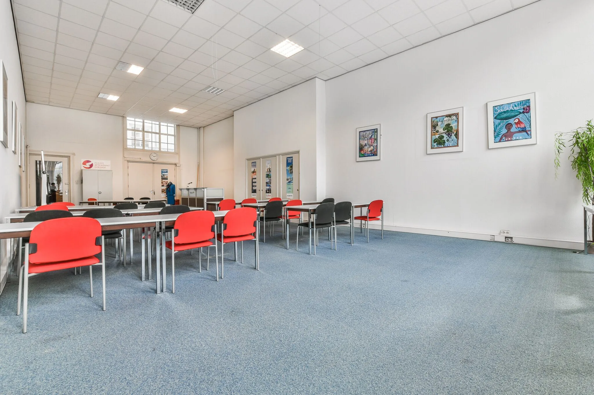 Vergaderruimte aan de Herengracht met rode en zwarte stoelen, blauwe vloerbedekking en kunst aan de muur.