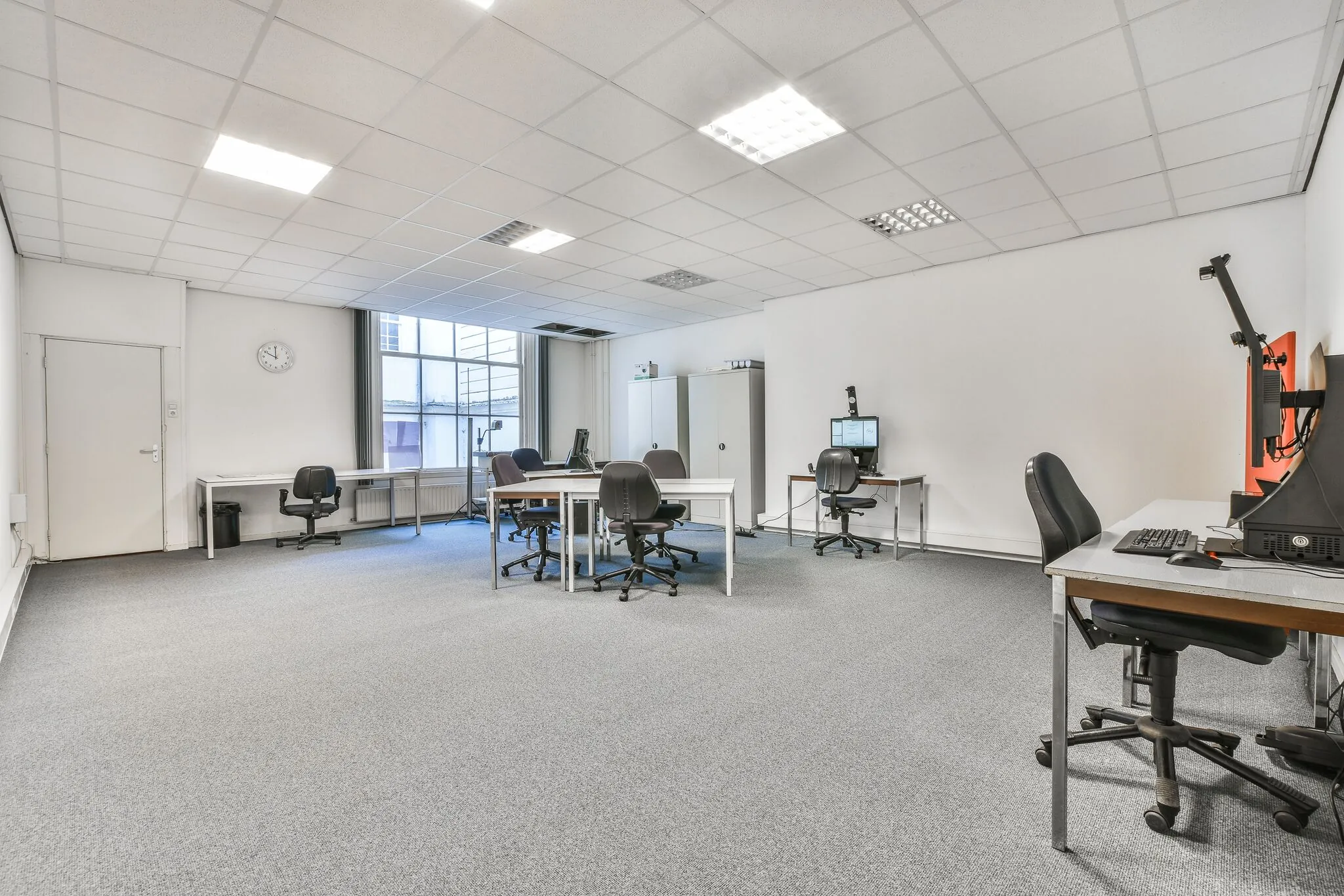 Licht en ruim kantoor aan de Herengracht met meerdere bureaus, bureaustoelen en computers.