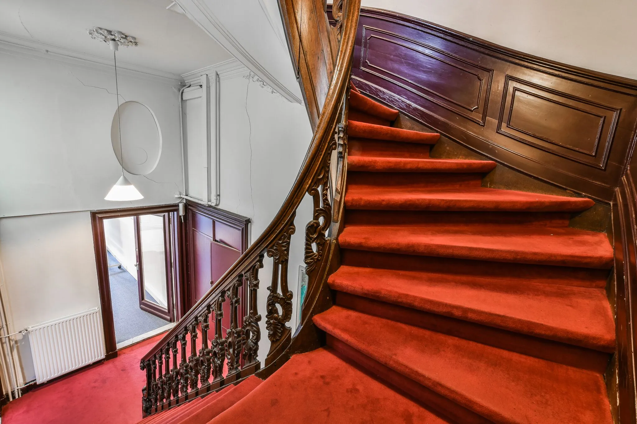 Trap met rode loper en houten leuning in een klassiek grachtenpand aan de Herengracht.