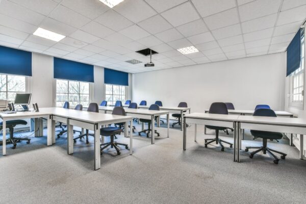 Licht en modern leslokaal aan de Herengracht met meerdere bureaus, bureaustoelen en een computeropstelling.