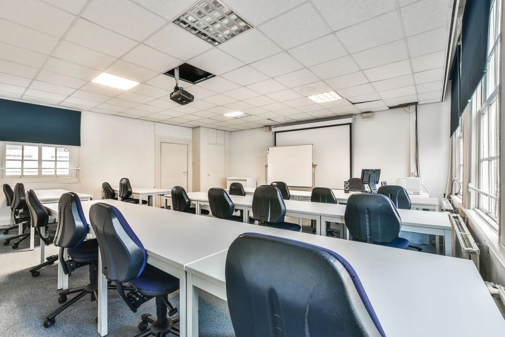 Leslokaal met bureaus, stoelen, een projector en een whiteboard aan de Herengracht.