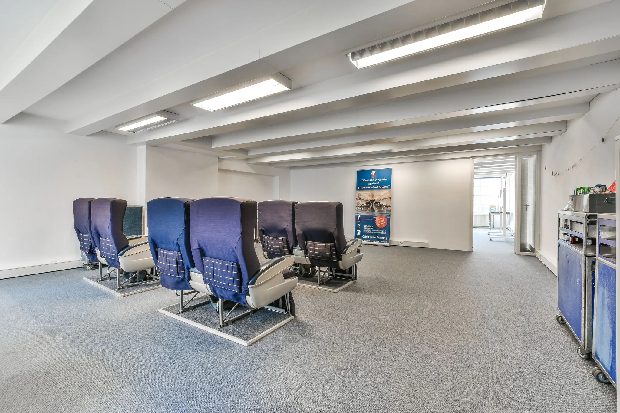 Trainingsruimte met vliegtuigstoelen en trolleys voor cabinepersoneelstraining aan de Herengracht.
