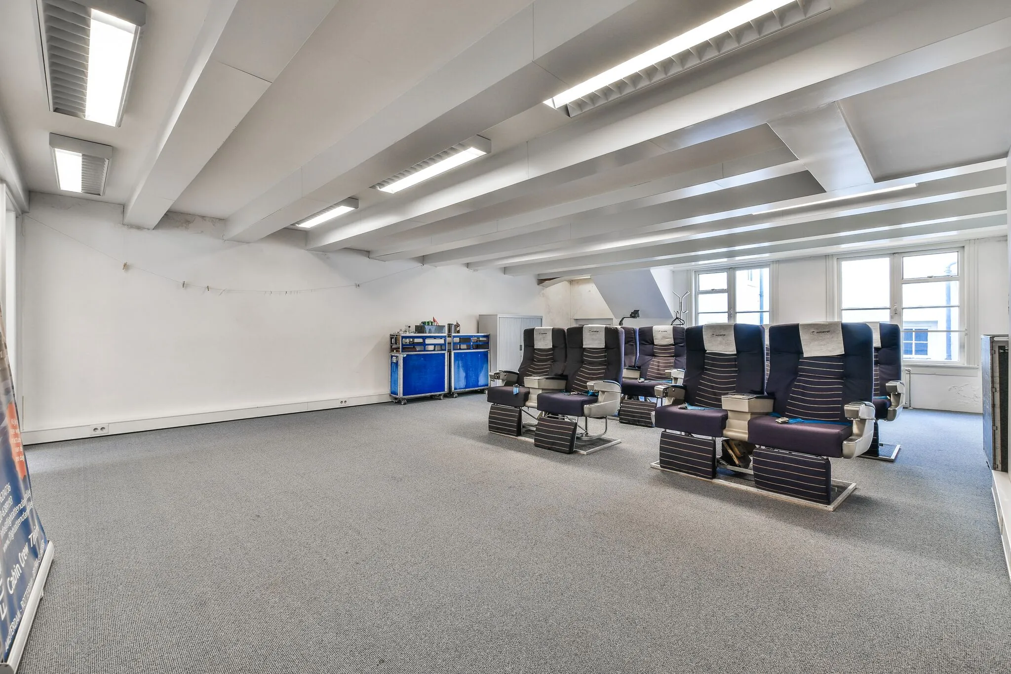 Ruimte in een kantoor aan de Herengracht met vliegtuigstoelen in opstelling, vermoedelijk gebruikt als trainings- of simulatieruimte.