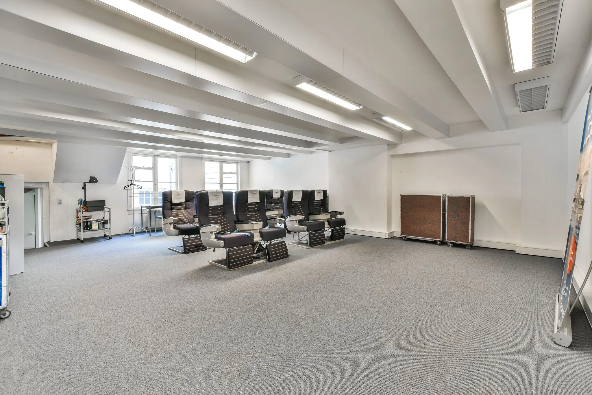 Ruime trainingsruimte met vliegtuigstoelen op Herengracht, ingericht als simulatie- of oefenruimte.