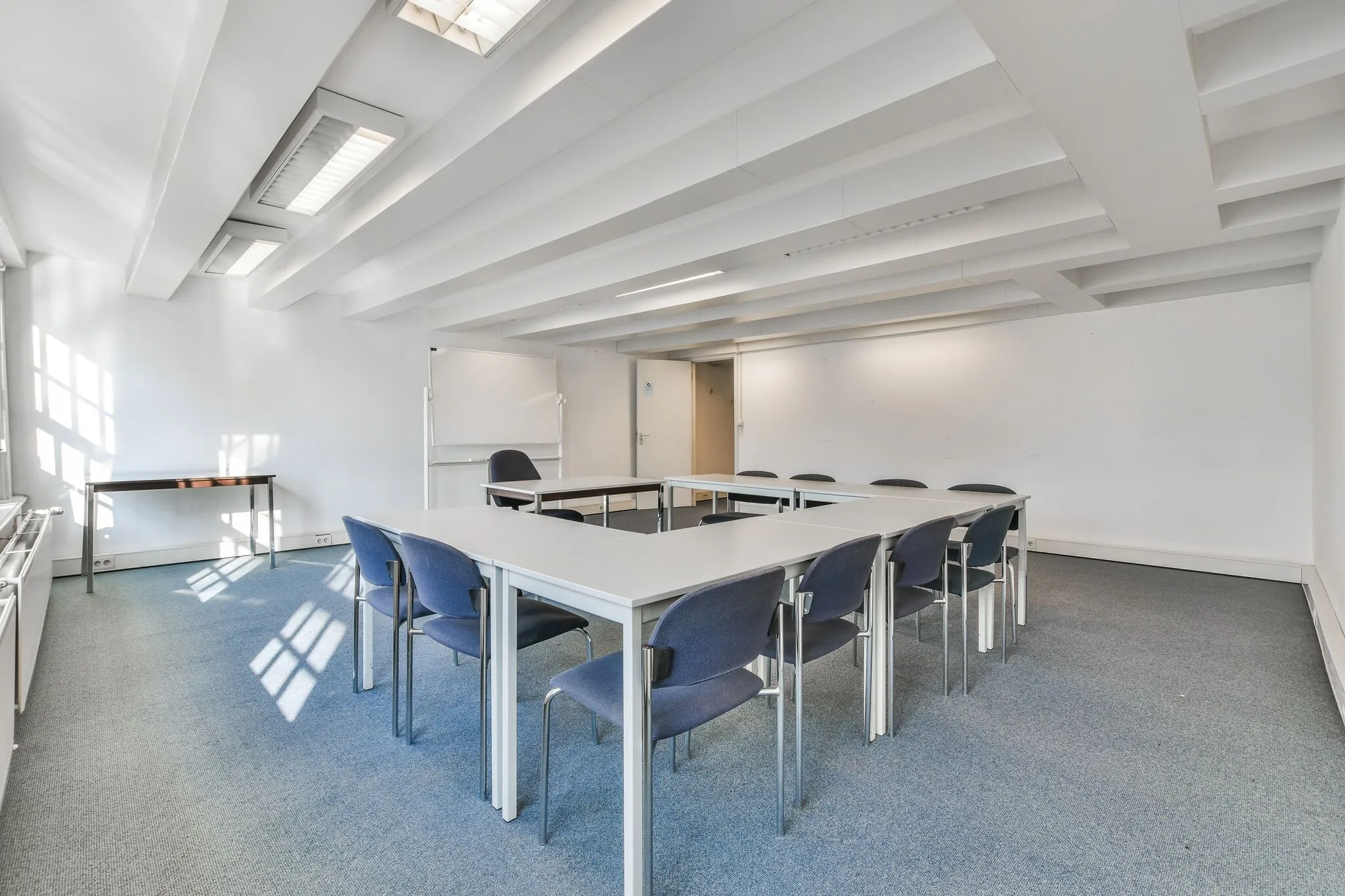 Vergaderruimte aan de Herengracht met U-vormige tafelopstelling, blauwe stoelen en wit interieur.