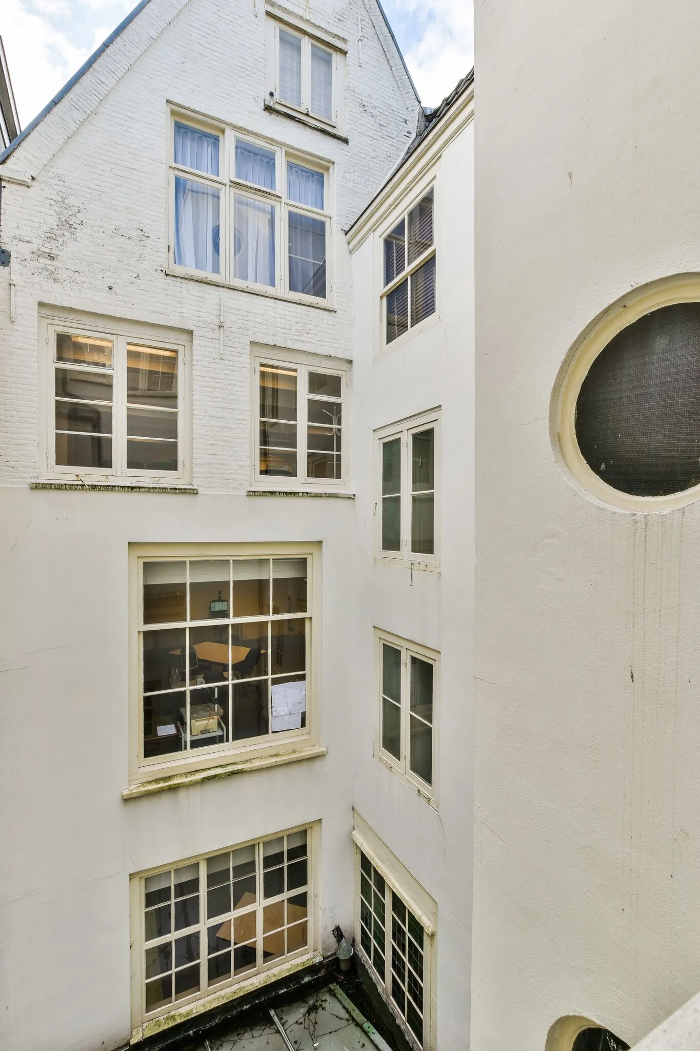 Binnenplaats van een klassiek Amsterdams grachtenpand aan de Herengracht met witgeschilderde gevels en meerdere ramen.