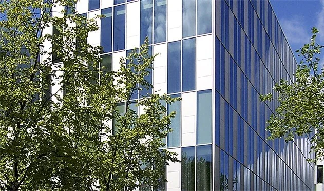 Modern kantoorgebouw aan de Benthemstraat met een gevel van glas en witte panelen, gefotografeerd op een zonnige dag.