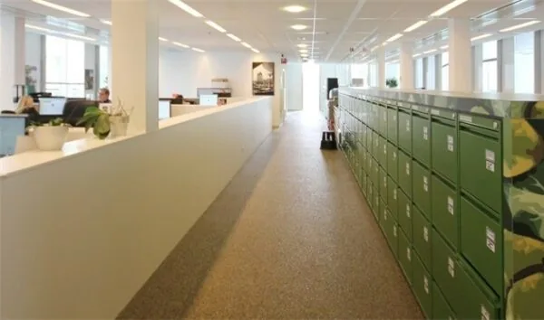 Modern kantoorinterieur aan de Benthemstraat met werkplekken links en groene opbergkasten rechts.