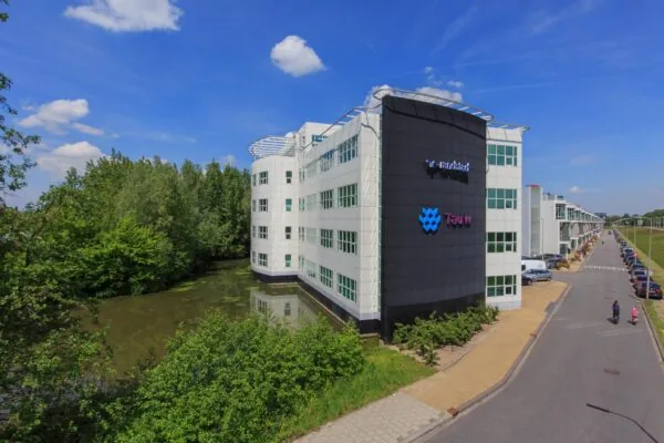 Modern kantoorgebouw van Tauw aan het Rhijnspoor, gelegen naast water en een groenstrook.