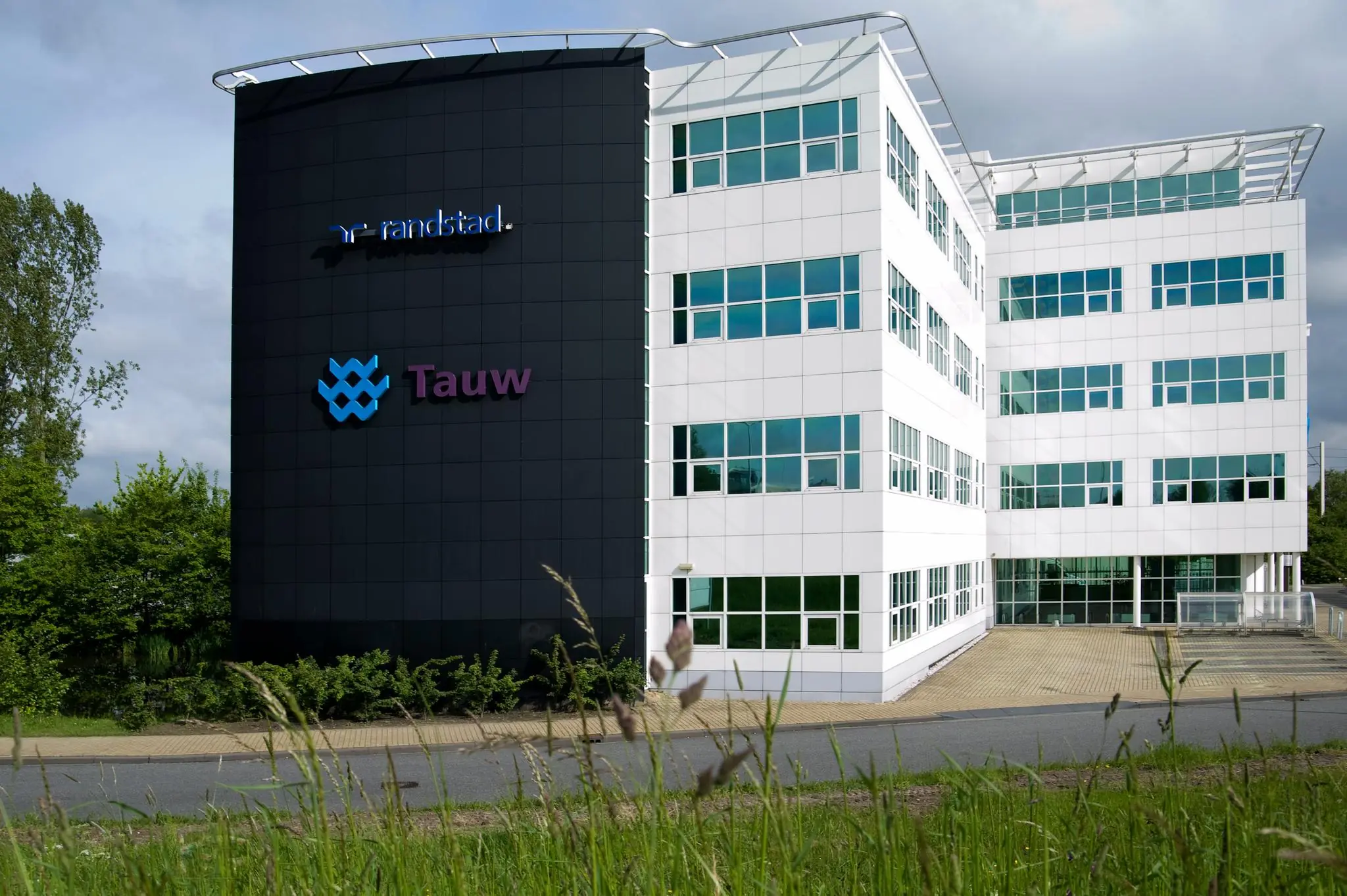 Wit kantoorgebouw aan het Rhijnspoor met de logo’s van Randstad en Tauw op de gevel.