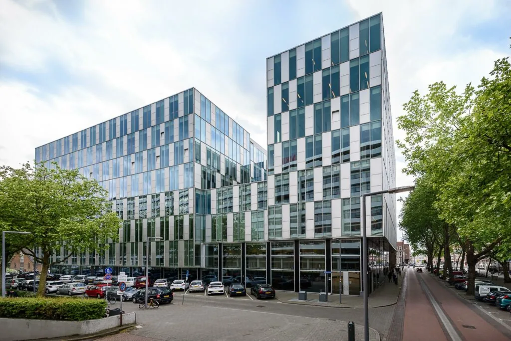Modern kantoorgebouw aan de Benthemstraat met glazen gevel en parkeergarage op de voorgrond.
