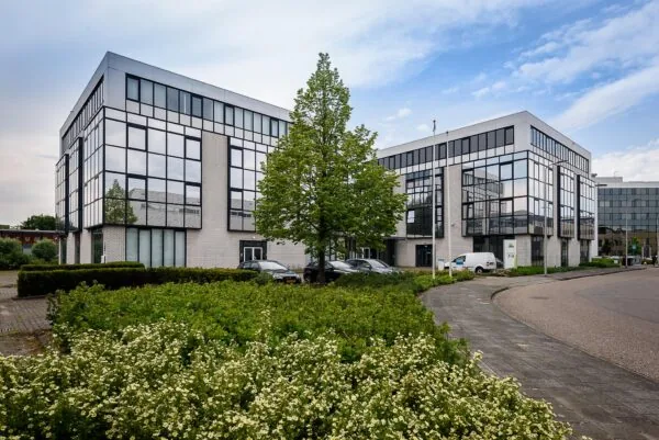 Modern kantoorgebouw aan de Cypresbaan met spiegelende ramen, parkeervakken en omliggend groen.