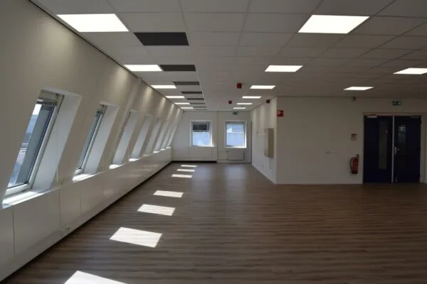 Lichte, lege kantoorruimte aan de Twentestraat met schuine ramen en houten vloer.