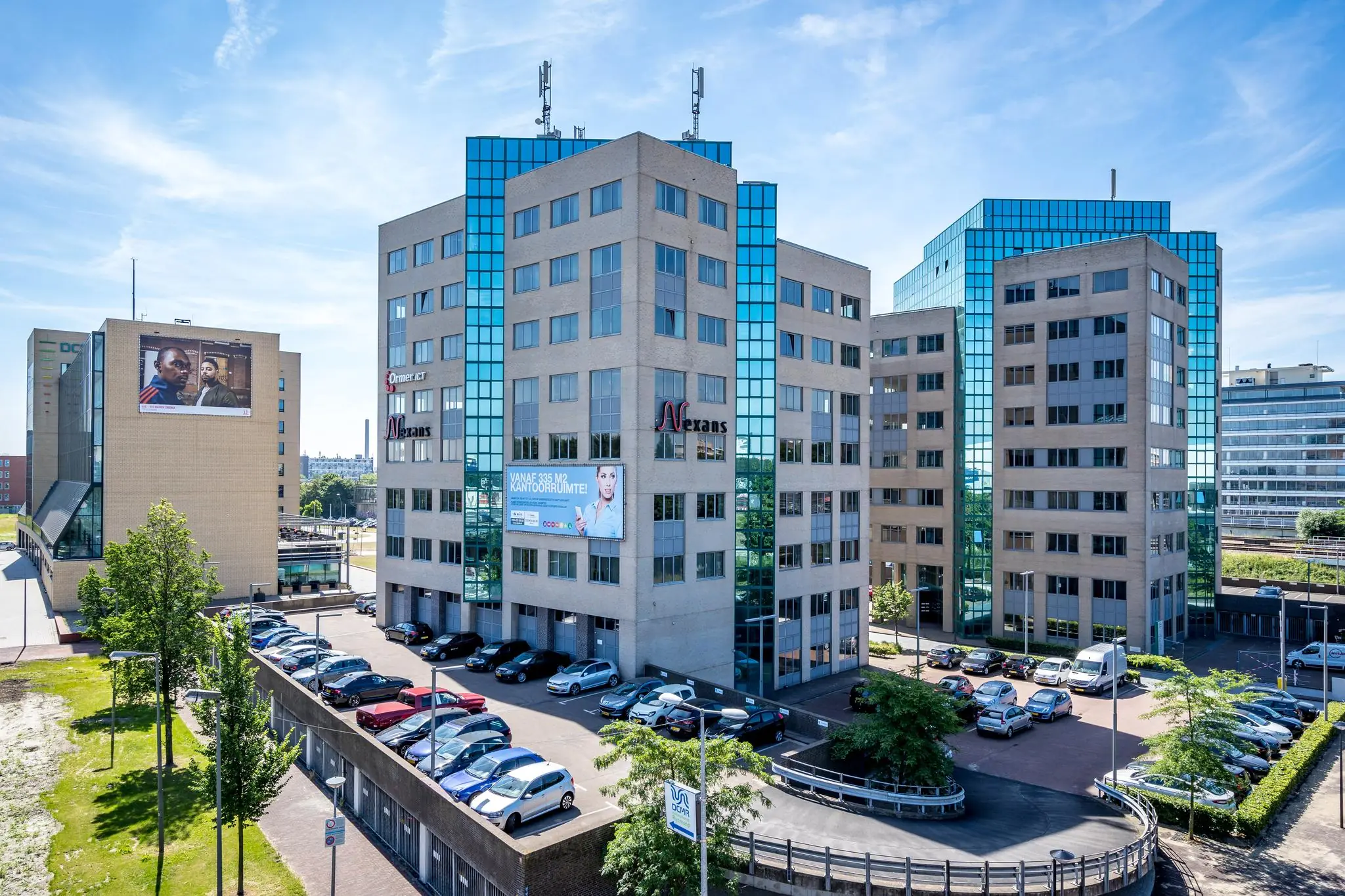 Kantoorgebouw aan de Overschieseweg in Rotterdam met bedrijfsnamen en parkeerplaatsen op de voorgrond.