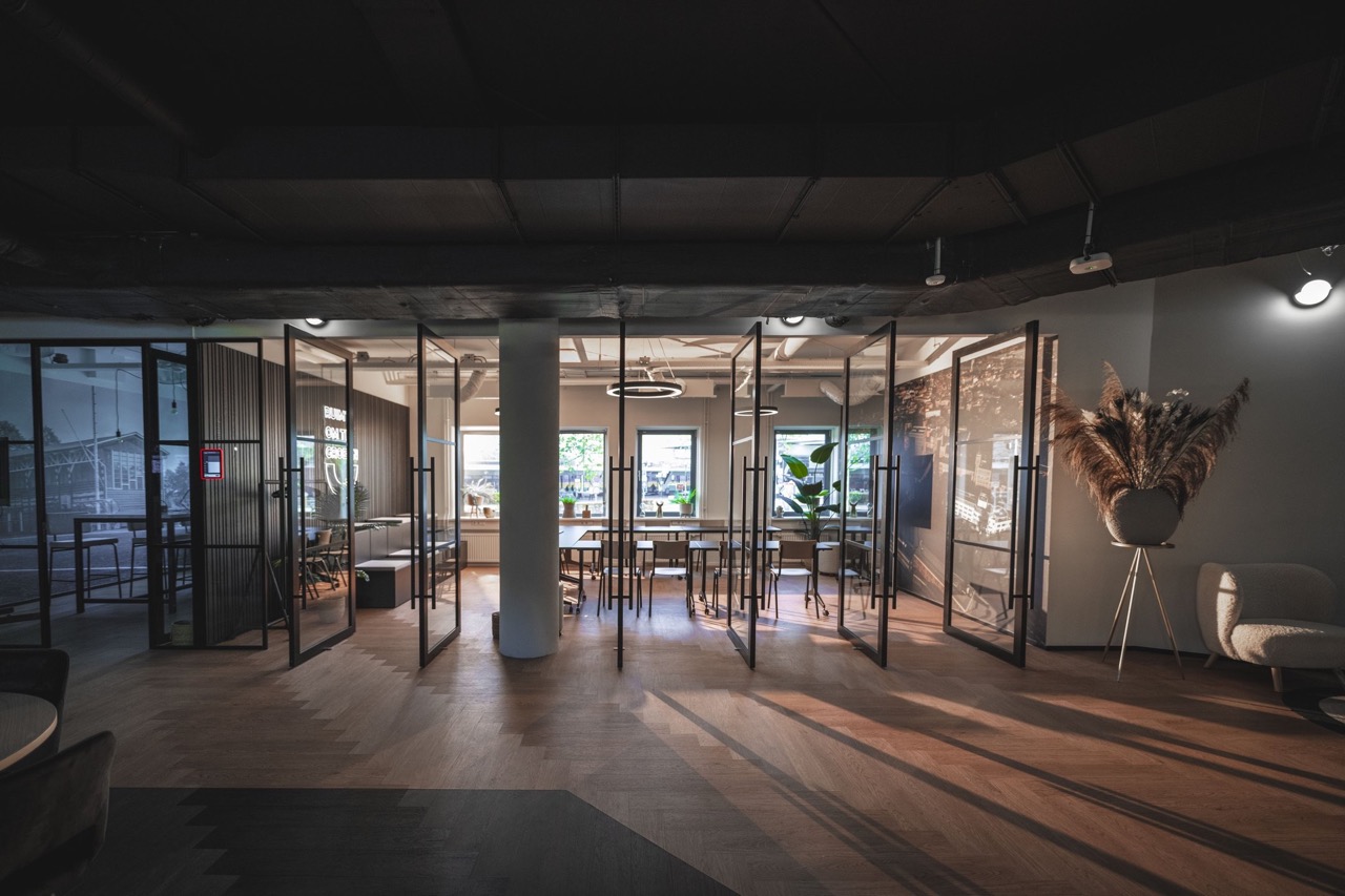 Modern kantoorinterieur met glazen vergaderruimtes, houten vloer en natuurlijk licht van drie ramen.