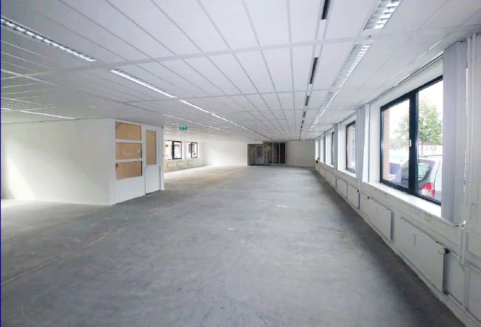 Leeg kantoorpand met systeemplafond en grote ramen aan het Stationsplein.