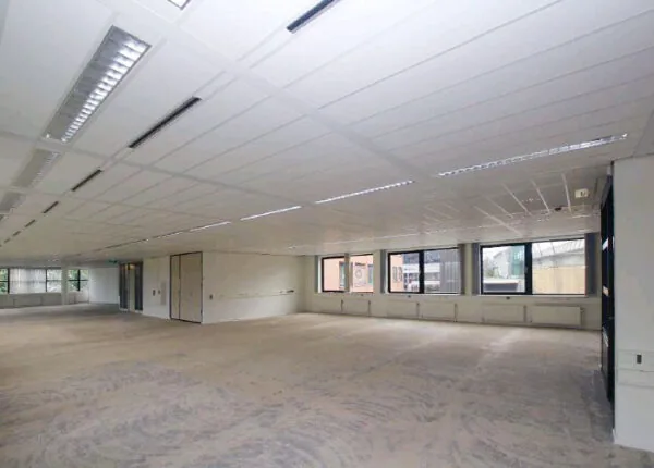 Leeg kantoorpand met systeemplafond en grote ramen aan het Stationsplein.