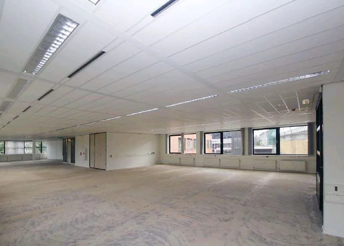 Leeg kantoorpand met systeemplafond en grote ramen aan het Stationsplein.