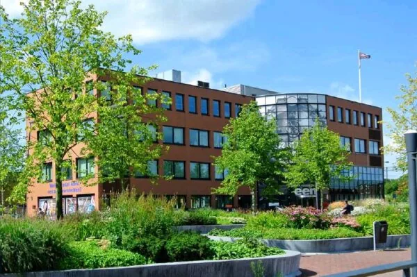 Modern kantoorgebouw aan het Stationsplein met groene beplanting op de voorgrond.