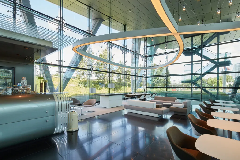 Moderne, lichtovergoten lounge met glazen wanden en designmeubilair aan de Amstelveenseweg.