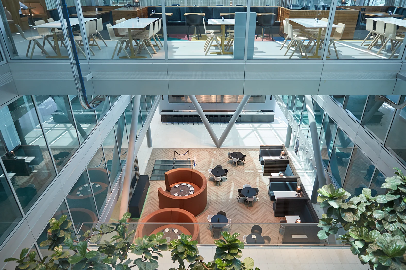 Moderne, open kantoorlobby aan de Amstelveenseweg met zithoeken, tafels en glazen wanden op meerdere verdiepingen.
