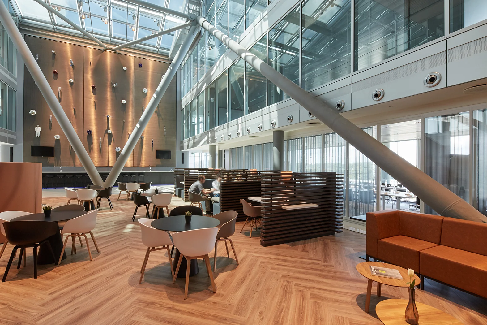 Moderne, open kantoorlobby aan de Amstelveenseweg met hoge glazen wanden, zitgedeeltes en kunstwand.