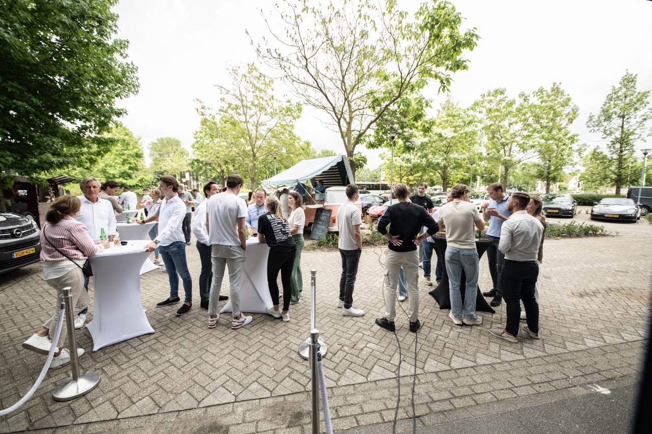 Groep mensen staat buiten bij statafels tijdens de Workspace Rally 2023.