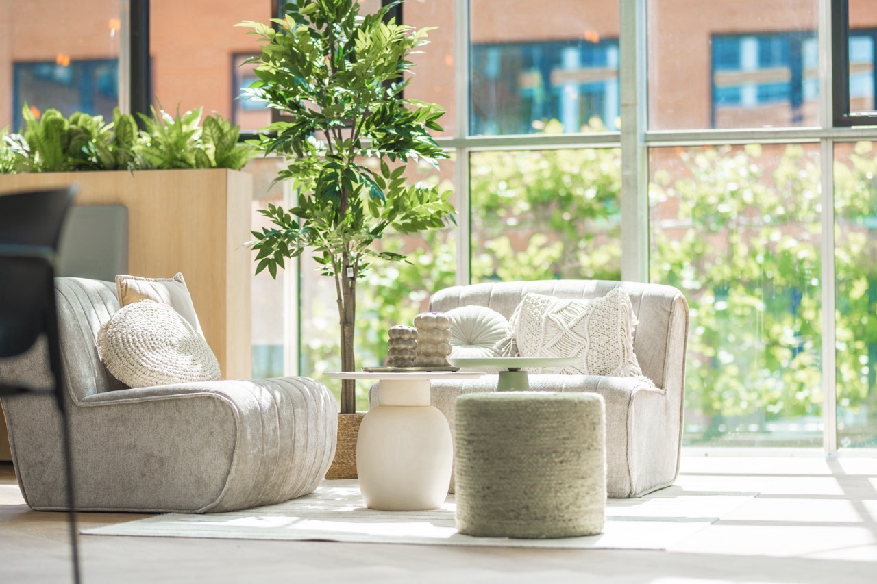 Lichte en groene zithoek in Sociaal Hart 24 met comfortabele stoelen, planten en veel daglicht.