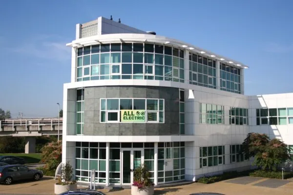 Modern kantoorpand aan het Rhijnspoor met een "All Electric"-bord op de gevel.