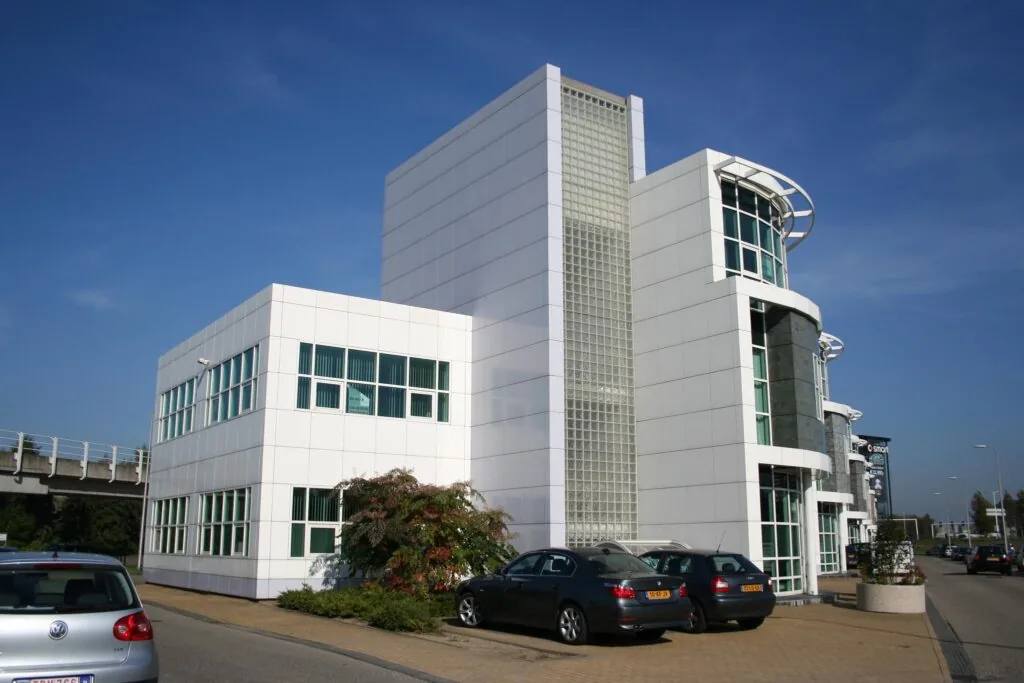 Modern wit kantoorgebouw aan de Rhijnspoor met parkeergelegenheid en gebogen glasgevels.