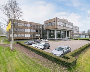 Modern kantoorpand aan de Bolderweg 1 in Almere met parkeerplaatsen en vlaggenmast op de voorgrond.