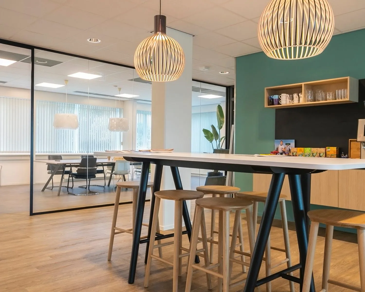 Moderne kantoorruimte aan de Bolderweg 2a in Almere met hoge tafel, barkrukken en glazen vergaderruimte op de achtergrond.