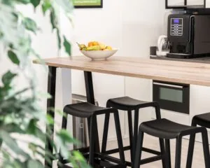 Moderne kantoorkeuken aan de Pascallaan 60-78 in Lelystad met hoge tafel, zwarte barkrukken en een fruitschaal.