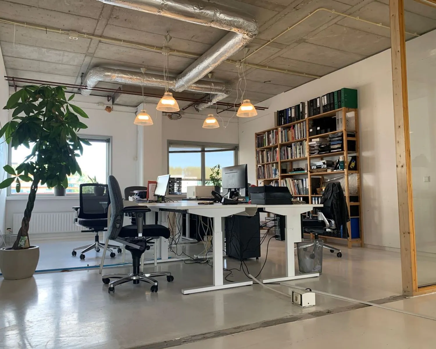 Moderne kantoorruimte met werkplekken, planten en boekenkast aan de Anthony Fokkerweg 21 in Amsterdam.