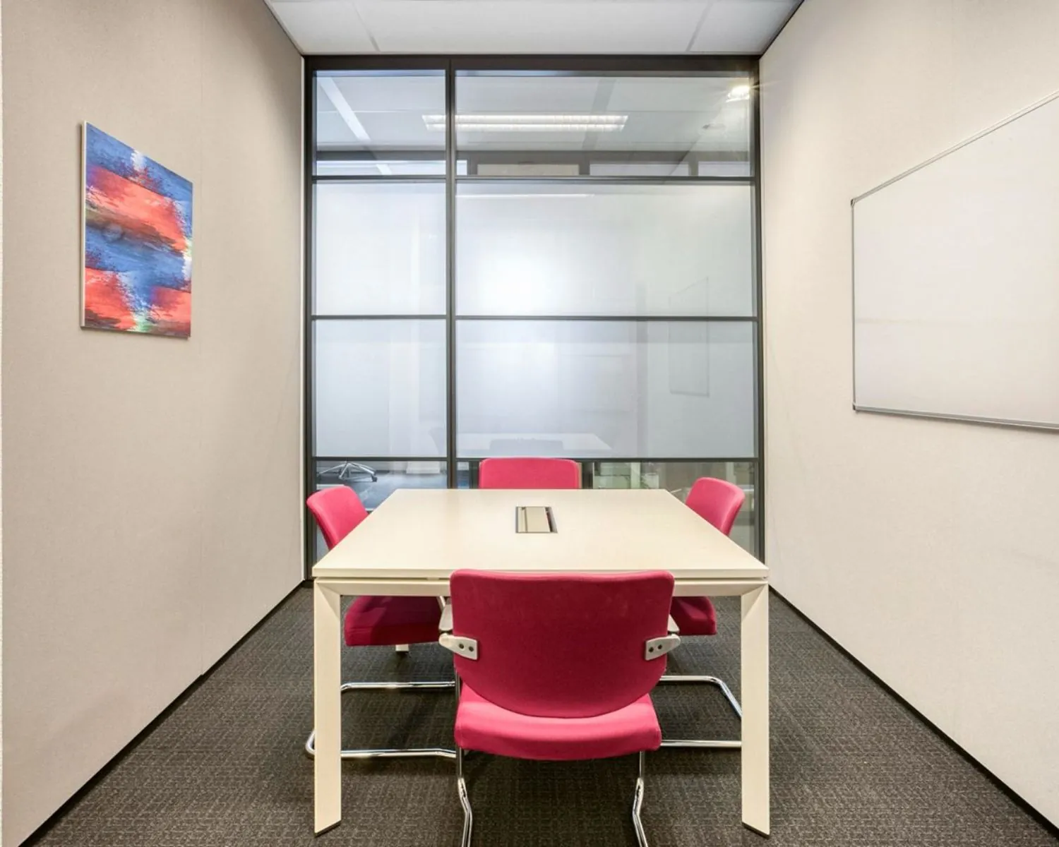 Moderne vergaderruimte met glazen wand, witte tafel en roze stoelen in Flight Forum 40, Eindhoven.