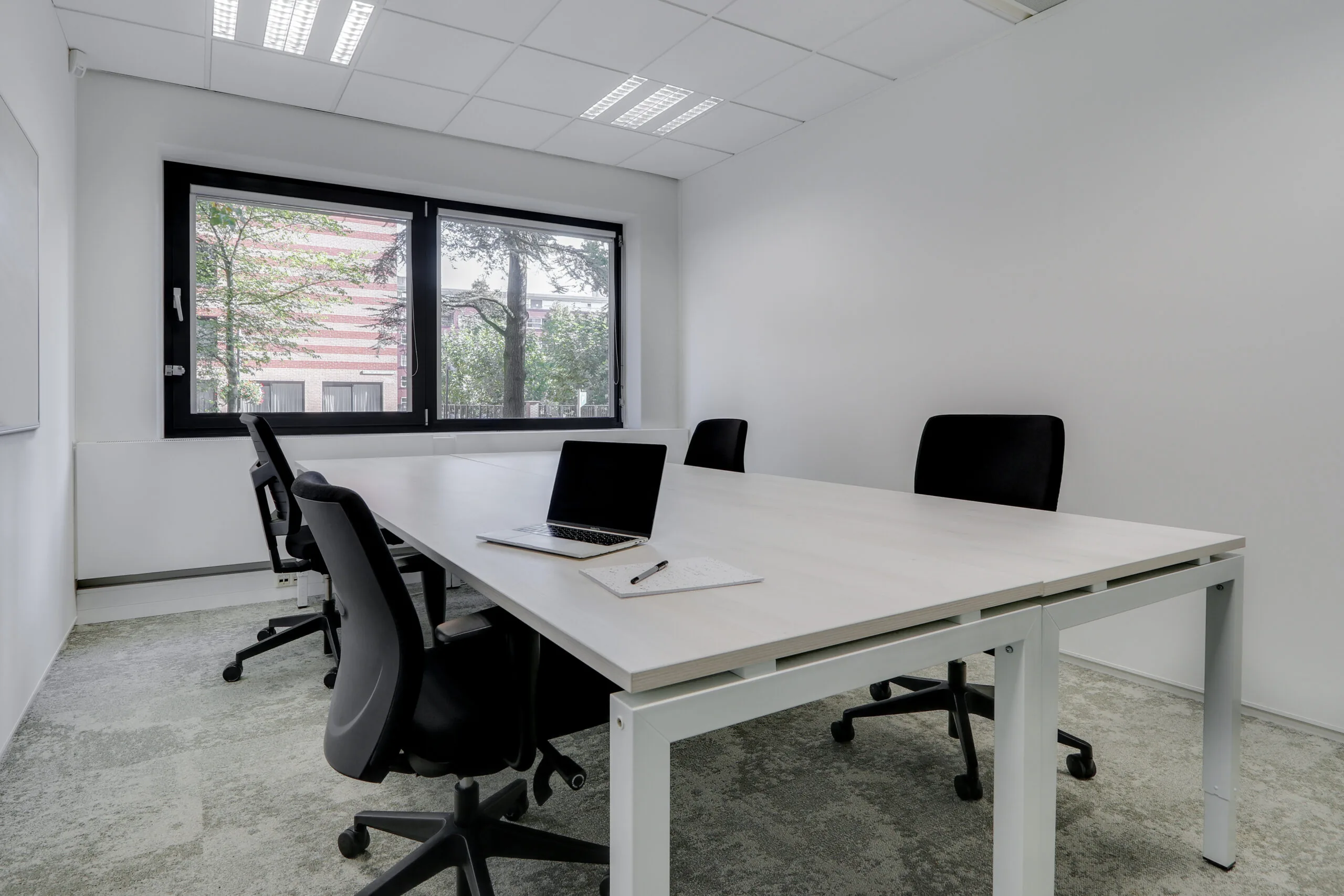 Moderne en lichte vergaderruimte in Utrecht Centraal-Workspace met een grote tafel, bureaustoelen en een laptop.