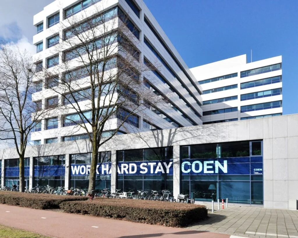 Modern kantoorgebouw Coengebouw aan de Kabelweg 37 in Amsterdam met de tekst "Work Hard Stay Coen" op de gevel.