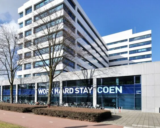Modern kantoorgebouw Coengebouw aan de Kabelweg 37 in Amsterdam met de tekst "Work Hard Stay Coen" op de gevel.